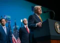 President Donald Trump speaks at a podium during a public event with US officials standing behind him.