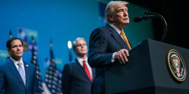 President Donald Trump speaks at a podium during a public event with US officials standing behind him.